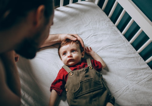 Dad loving his kid in the crib