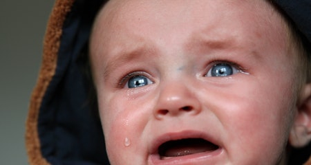 Baby crying in brown and black hooded top