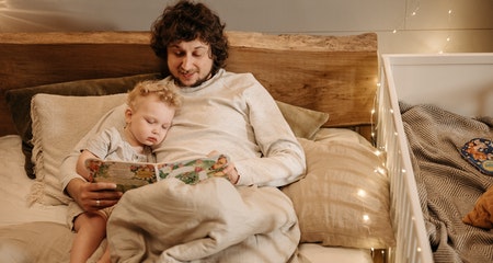 Dad trying to get his baby to fall asleep on the bad next to the baby crib