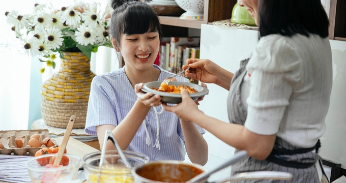 Happy woman eating pasta and eggs Benedict during pregnancy