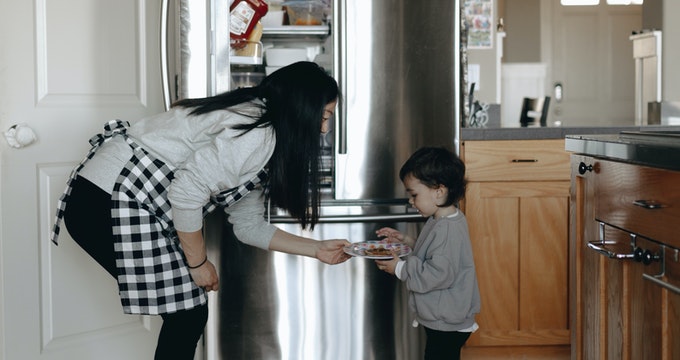 Mother giving her kid food in the kitchen