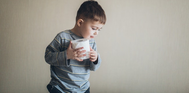 A toddler holding a toilet paper