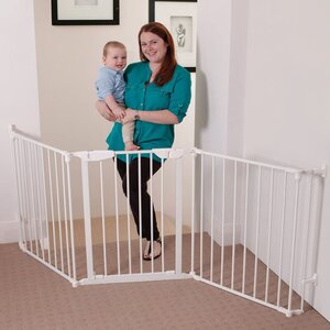 A mom is holding her baby next to the Dreambaby Newport Adapta Baby Gate