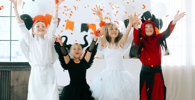 4 teenage girls celebrating Halloween wearing halloween costumes