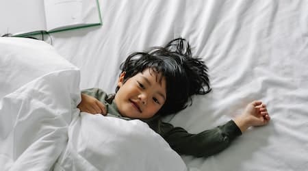 Ethnic boy lying in bed after sleep